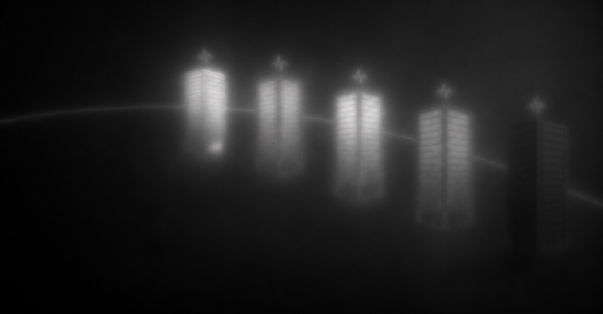 Five office towers illuminated through the fog.
